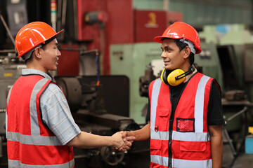 Happy smiling teamwork technician engineer or worker in protective uniform with hardhat shaking hands celebrate successful together completed deal commitment at heavy industry manufacturing factory