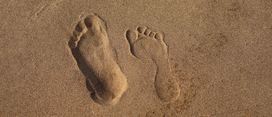 Male and female footprint on sand