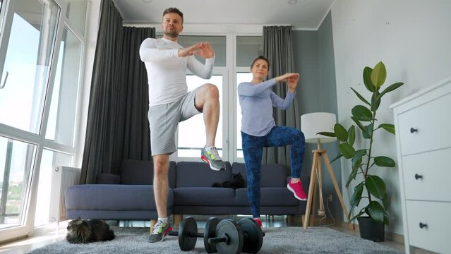 Caucasian couple doing cardio training at home in cozy bright room