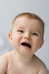 Portrait of happy baby girl with opened mouth looking away at home.