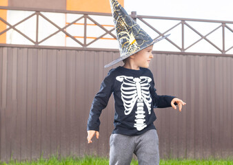 Child in halloween costume with skeleton and witch hat