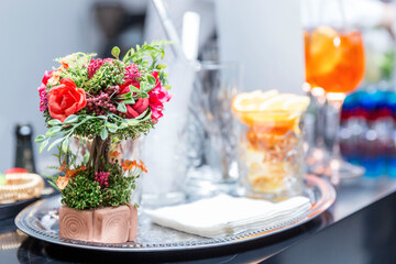 A romantic bouquet of flowers on the bar with drinks in glasses. Leisure and holidays.