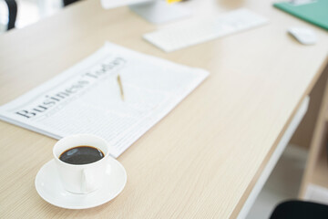 Coffee mugs and newspapers on the desk at the office.