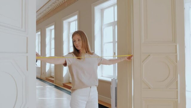 Female interior designer measuring distance with tape at door entrance for wedding event