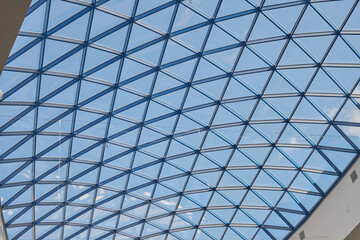 Background image of a transparent glass roof with a metal frame in the shape of a diamond. glass roof shopping center. The ceiling in the shopping center...