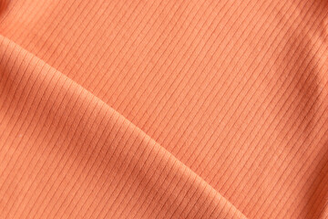 Folded ribbed cotton fabric texture pastel orange  . Close up rib cotton cloth and textiles pattern. Natural organic fabrics texture background.
