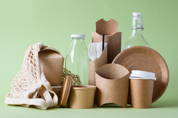 Items made from environmentally friendly biodegradable materials to reduce the level of plastic waste on a green background. The concept of zero waste. Eco-friendly tableware.