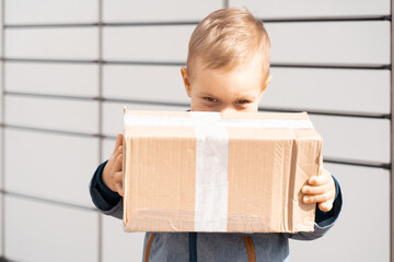 Parcel delivery, pickup point with lockers, kid with parcel, contactless pack delivery. Child parcel, boy using self service parcel terminal machine to send or receive package