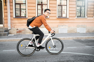 A male cyclist goes to work with a briefcase. Urban ecotransport. - obrazy, fototapety, plakaty
