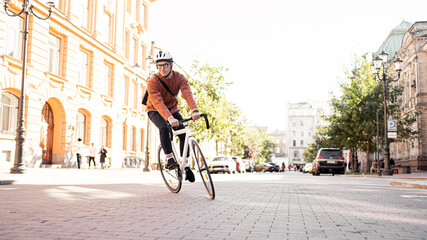 A cyclist in a helmet goes to work with a briefcase. Urban ecotransport.  Fitness watch on hand.