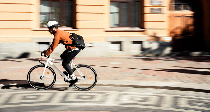 Blurry photo. Urban transport.  A cyclist goes to work with a briefcase. .