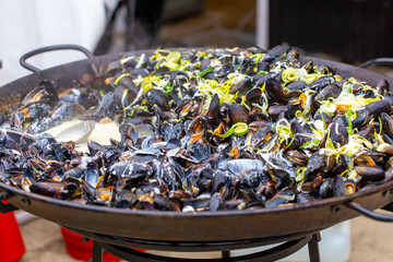 Mussels cooked in wine sauce with herbs in a large frying pan