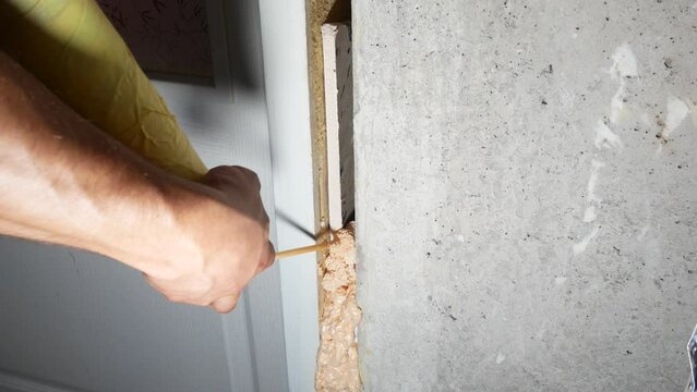 Worker is installing the door with a spray foam insulation. Repair works. Maintenance in the apartment. Polyurethane foam.