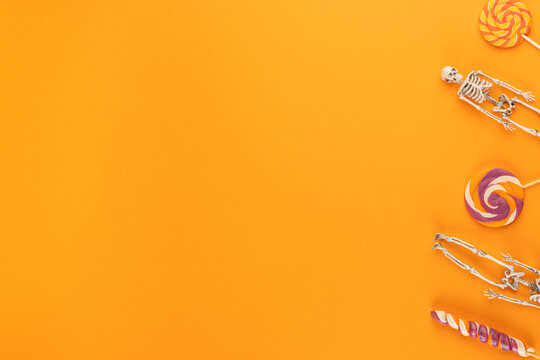 halloween decorations on orange background. Halloween concept. Lollipops and toy skeleton. top view copy space. holiday autumn fall