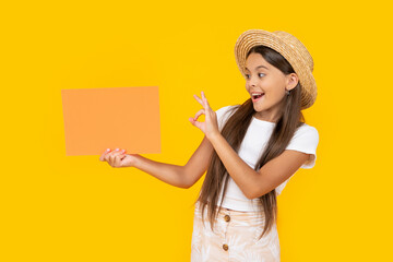 amazed teen girl with copy space on orange paper on yellow background. ok