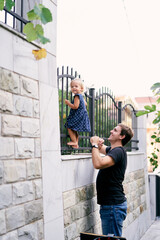 Fototapeta na wymiar Dad looks at a little girl standing on a metal fence. High quality photo