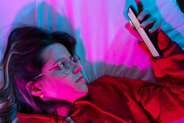 Doom scrolling on bed at night with neon lights. Technology at bed concept.