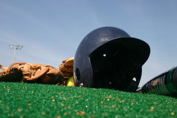Low angle of batting helmet on pitchers mound with gloves and bat