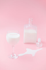 glass with milk and a graph in the background. pink background. puddle of spilled milk.