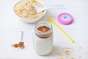 Morning healthy breakfast. Cocoa milk and oatmeal granules. Wooden white background.