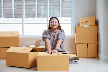Asian woman startup packaging  business, holding parcel box, order by online at her home.