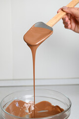 The process of tempering chocolate and making chocolates. Pastry chef using spatula tempering molten chocolate