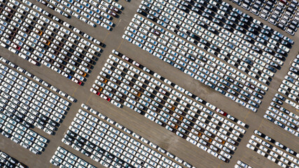 Aerial top view parked new cars at the automotive plant, new car lined up in the port for import and export business logistic to dealership for sale, Automaker distribution center with new vehicles. © Darunrat