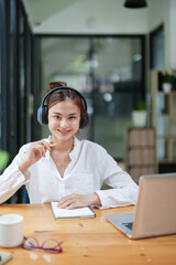 woman using computer, earphone and notebook during a video conference