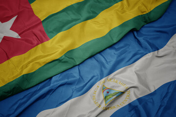 waving colorful flag of togo and national flag of nicaragua. 3d illustration