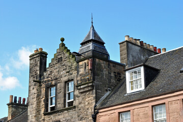Fototapeta na wymiar Old Stone Building with Chimneys seen against Blue Sky 