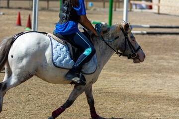 Little girl that rides a white pony during Pony Game competition at the Equestrian School