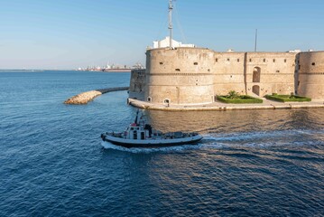 Small Tug  thet exits from the Taranto Canalboat in summer, in front of the Aragonese Castle