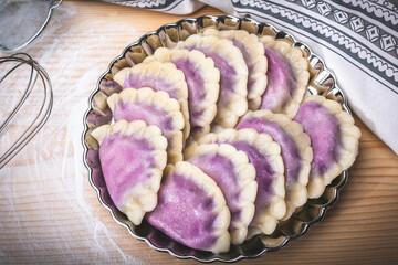 Traditional Polish pierogi with blueberries, on a wood counter. Sweet dumplings with fruit, on a plate, top view