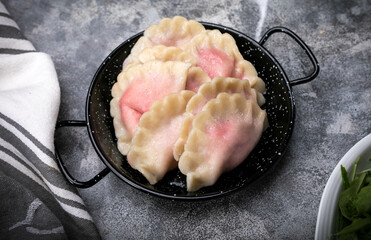 Traditional Polish pierogi with strawberries, on a stony counter. Sweet dumplings with fruit, on a...