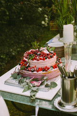 Große zweistöckige Hochzeitstorte mit Beerencreme und frischen Beeren, dekoriert mit Himbeerkuchengrün-Hochzeitszeremonie