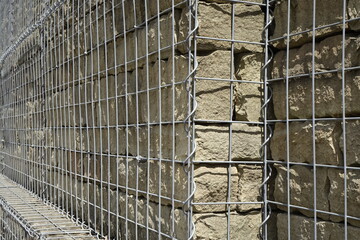 Massive yellow quartzite granite wall behind mesh wire, sunny spring day, concept: protection, defence (horizontal), Wolfstein, RLP, Germany