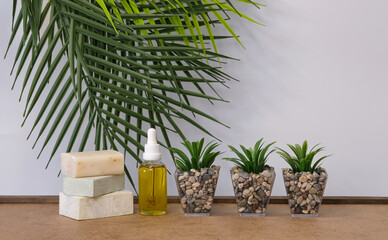 spa concept - soaps, essencial oil and plants infront of green leaves