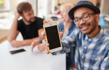 Black man showing smartphone near friends