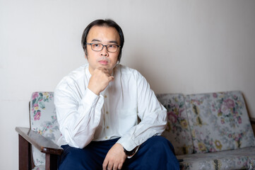 Fototapeta premium Asian's young man wear white shirt and sitting on the sofa.