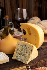 Varied cheese table, blue cheese Fontina Gruyer Cheese Teetilla in wooden table with red wine glass Pimentero oil and Round homemade fields of field and rustic knife