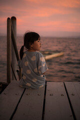 海で座って綺麗な夕焼けの空をみている女の子