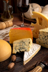 Varied cheese table, blue cheese Fontina Gruyer Cheese Teetilla in wooden table with red wine glass Pimentero oil and Round homemade fields of field and rustic knife