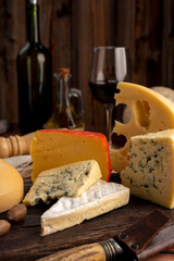 Varied cheese table, blue cheese Fontina Gruyer Cheese Teetilla in wooden table with red wine glass Pimentero oil and Round homemade fields of field and rustic knife