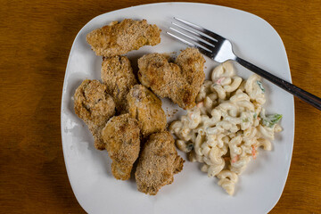 baked chicken  wing arranged on a plate with macaroni salad