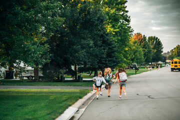 Three tween girls frantically run after a school bus