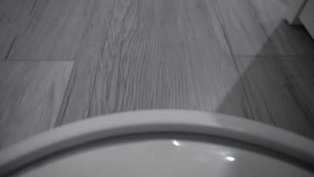Robot vacuum cleaner rides on a white parquet floo