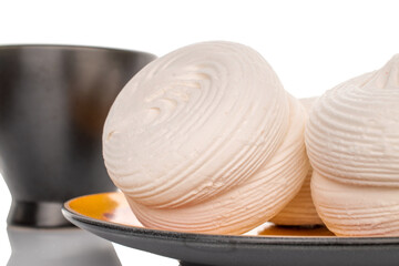 Two sweet white marshmallows on earthenware, macro, isolated on white background.