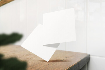 Clean minimal square flyer mockup floating on wooden table with plant