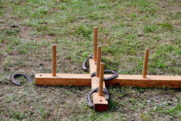 A close up on a wooden cross with pegs attached to it used to throw horseshoes at as a kind of medieval game recreated during a folk fair organized in Poland during summer