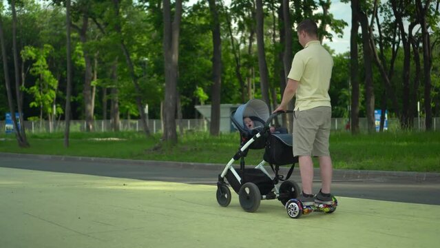 A young dad walks with a stroller on a hoverboard 